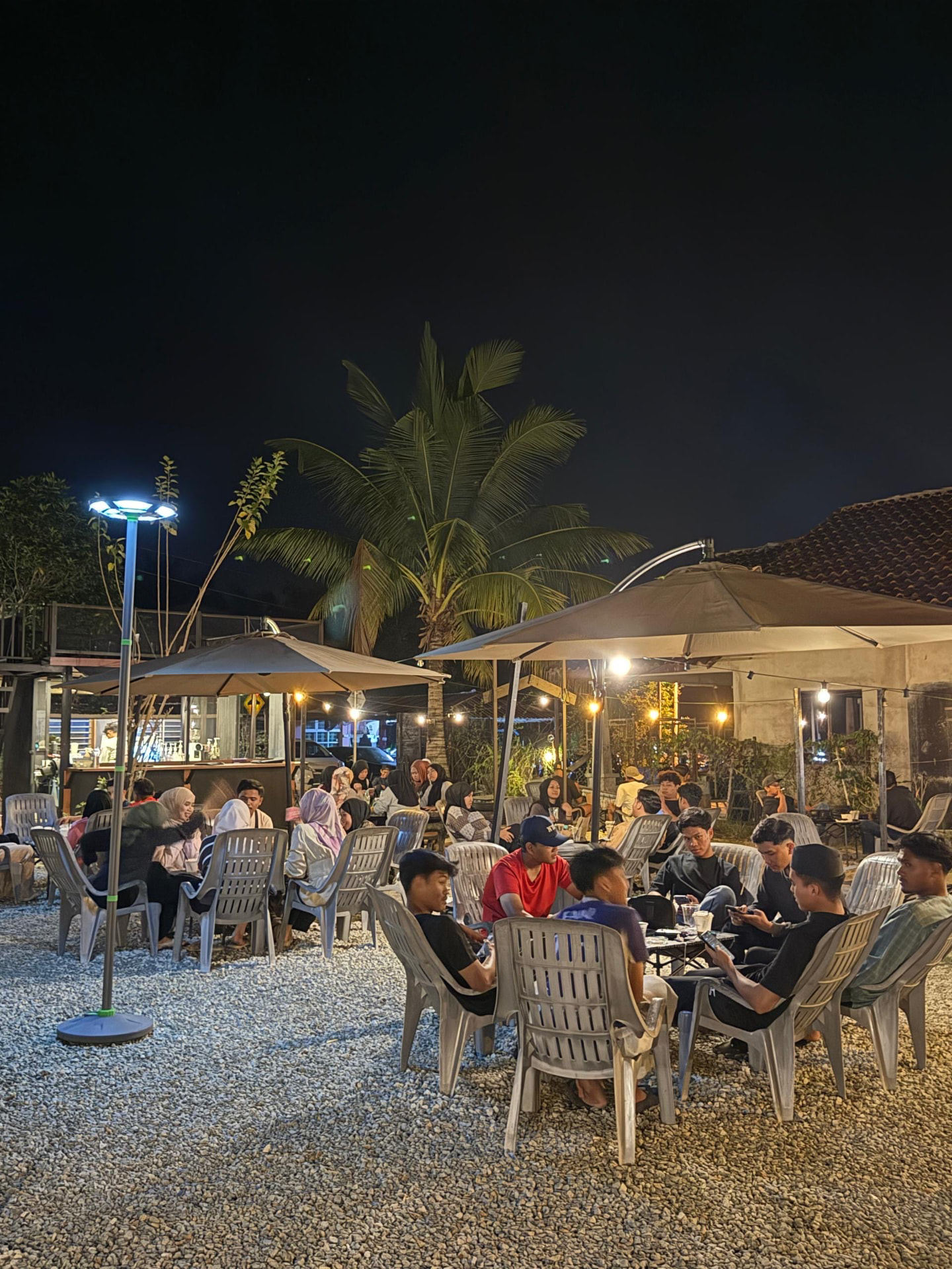 A full crowd seated outside Kopi Turu at night